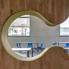 This playful, curved viewing window in a school environment is an example of how we craft moments of delight and curiosity. It transforms a simple partition into an engaging architectural feature that encourages interaction and visual connection between spaces.