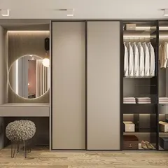 We design wardrobes that are more than just storage; they are personal styling zones. This custom walk-in unit features a mix of open shelving, glass-door cabinets for visibility, and a dedicated vanity nook with a round mirror, blending organization with pure elegance.