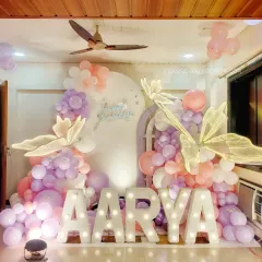 We can transform any space for a magical celebration. This butterfly-themed first birthday features pastel balloons, large lighted marquee letters spelling the name 'AARYA', and beautiful butterfly accents.
