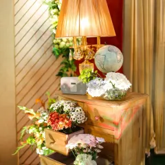 A charming vintage corner. I styled this nook with a rustic chest of drawers overflowing with flowers, a classic lamp, and a small globe to add a touch of timeless elegance and personality.