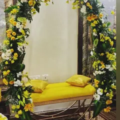 A simple yet elegant seating arrangement for a Haldi or Mehendi ceremony. The yellow bench is framed by a beautiful arch of yellow and white flowers, creating a perfect photo spot.