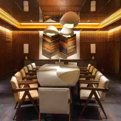 For the Bammi Residence's basement dining room, we transformed a space without natural light into an opulent, jewel-box-like chamber. The walls and ceiling are enveloped in intricate Pinjirakari-inspired lattice work, a traditional craft that creates a warm, filtered glow. The bespoke dining table and curated art pieces complete this immersive and atmospheric dining experience.
