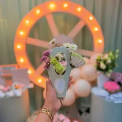 Holding a small bouquet against the backdrop of the Parisian baby shower decor, showing how floral elements were woven throughout the event.