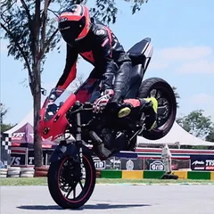 While we focus on racing, we appreciate all forms of skill. A rider performs a wheelie, showcasing incredible bike control on our track during a stunt session.