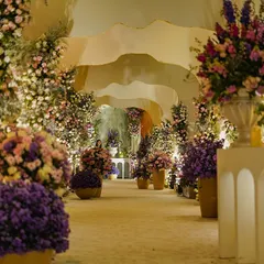A breathtaking floral pathway from our 'Lilac & Gold' themed event. The aisle is lined with an abundance of flowers in shades of purple, pink, and white, creating a truly immersive and romantic entrance for guests.