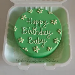A simple and sweet bento cake for a birthday. This green mini cake is decorated with tiny white flowers and a "Happy Birthday Baby" message, perfect for a small, heartfelt celebration.
