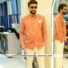 A client models our peach-colored Jodhpuri jacket with subtle self-colored floral embroidery. Paired with off-white trousers, this is a perfect outfit for a daytime wedding event.