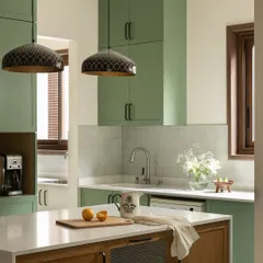 This kitchen from the Earthy Hacienda home is designed for both beauty and function. The sage green cabinetry, warm oak island, and patterned pendant lights come together to create a space that is a joy to cook and gather in.