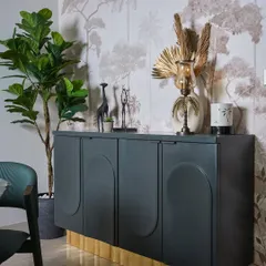 A customized MDF console with gold-leaf skirting serves as a luxe crockery storage solution. It is styled with a statement wallpaper backdrop and decorative vases.