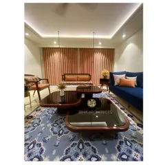 This view highlights the complete living room arrangement, including a traditional wooden swing and a multi-tiered coffee table. The combination of different seating styles provides flexibility for family gatherings and entertaining, all unified by a classic patterned area rug.
