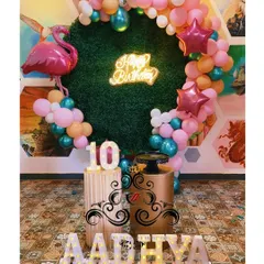 For birthdays, I bring any theme to life. This tropical jungle theme for a 10th birthday includes a custom grass backdrop, a neon 'Happy Birthday' sign, themed balloon arrangements, and light-up marquee numbers.