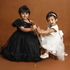 Two sisters, dressed in beautiful black and white gowns, share a playful moment. This image captures the unique bond and personalities of siblings.