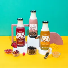 A clean and modern product shot for Zen Boba, showcasing three different flavors in their branded bottles. This style uses bold, colorful backdrops and minimal props to make the packaged product the hero, perfect for e-commerce and advertising.