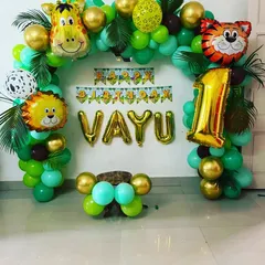 A simple yet beautiful jungle-themed balloon arch for Vayu's first birthday. We used shades of green and gold balloons, animal foil balloons, and palm leaves to create a stylish and festive decoration at home.