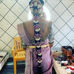 A modern take on the traditional floral braid. This hairstyle uses custom-made floral pieces in purple and white to perfectly match the bride's Kanjivaram saree.