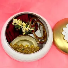 An inside look at the lotus-handle box, showing how neatly the traditional items are placed. It contains a half coconut, a blouse piece, and festive bangles.