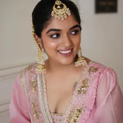 A radiant Punjabi bride in a beautiful pink lehenga. The makeup is fresh and glowing, with a defined eye and a matching pink lip to create a harmonious and joyful look.