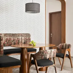 This cozy dining nook in our 'Palaash' project features a custom curved wall with built-in seating. The bold tribal-print upholstery is paired with a solid teak wood dining table.