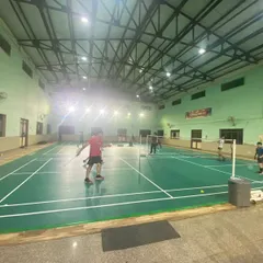 A wide-angle view of our well-lit indoor badminton hall during an evening session. We provide a professional environment for players to train in.