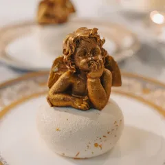 An edible golden cherub dessert, meticulously crafted for a dinner inspired by the art and architecture of Versailles. This piece showcases our passion for detailed, artistic pastry work that serves as a grand finale to a thematic meal.