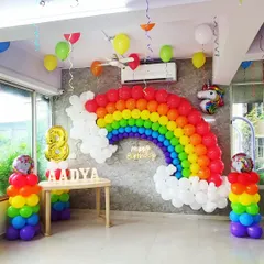 I built this large rainbow balloon arch against a grey wall for an 8th birthday party. The setup includes rainbow-colored balloon pillars, a unicorn foil balloon, and a lit-up 'Happy Birthday' sign to create a bright and cheerful unicorn-themed celebration.