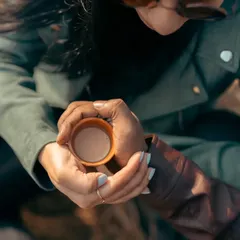 Love is sharing a warm cup of chai on a cool morning. This close-up focuses on their hands intertwined around a traditional clay cup, a simple and beautiful symbol of their bond.