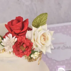 A close-up of the handmade red and white sugar flowers on the engagement cake.