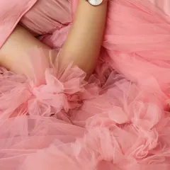 A macro shot capturing the delicate floral details and soft ruffles of a pink maternity gown, highlighting the quality and beauty of the outfits in my client closet.