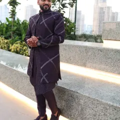 This purple open Indo-Western jacket features a unique geometric pattern created with hand and machine work. It's a bold and stylish choice for a Sangeet or cocktail party.