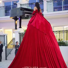 A view of the Piano Dress performer from behind, showcasing the incredible scale and drama of her cascading red gown. This is how you make a statement.