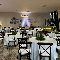 The interior of the real estate launch event, showcasing an elegant boho-white decor theme with classic cross-back chairs and clean, white table linens.
