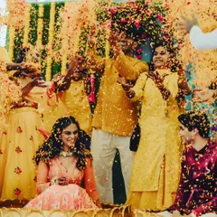 A Haldi ceremony moment that is pure chaos and joy. The bride is showered with flower petals by her loved ones, and her laughter is absolutely infectious.