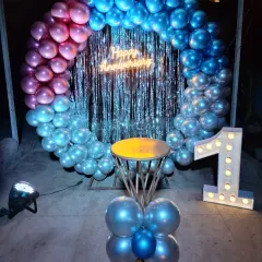 Anniversaries are so special, and I aim to create a truly romantic atmosphere. This first-anniversary setup features a stunning balloon ring with chrome balloons, a shimmering backdrop, and a neon sign, creating the perfect intimate corner for a couple to celebrate their journey.