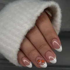 A classic French manicure with a playful, hand-painted cherry accent. This shows how you can add a touch of personality to a timeless look.