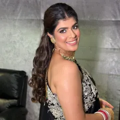 A chic and modern look for a wedding guest, featuring a half-up ponytail and soft waves.