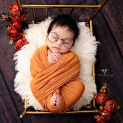 For the parents who love a touch of whimsy, we offer creative setups like this adorable 'little scholar' theme. Complete with tiny glasses, this baby is resting on a miniature golden bed, making for a truly unique portrait.