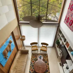 An aerial view of the Kavyam Residence living room shows the impact of the double-height glazed façade. This feature maximizes natural light and offers uninterrupted views of the green belt outside, enhancing the connection to the outdoors.