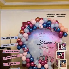 I designed this custom baby shower backdrop with a watercolor-style print and the mother's name. The setup includes a multi-colored balloon arch, 'BABY' display boxes, and fun signboards for a personalized photo booth.