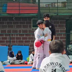 The moment before the match. I am observing two students as they prepare to spar, ensuring they maintain respect and sportsmanship even in competition.