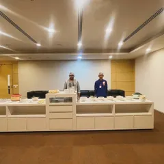 Our team ready to serve at a corporate event. The buffet is set up neatly on a long white counter in a modern office space, ready for the lunch rush.