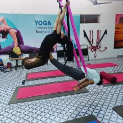 A beautiful partner aerial yoga pose that combines a backbend for the base with an inversion for the flyer, creating a deep stretch for both.