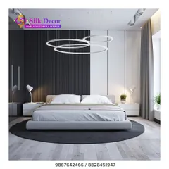 For clients who prefer a minimalist aesthetic, we design clean and contemporary pieces. This bedroom features one of our low-profile upholstered beds in a simple grey fabric, set against a striking black and white accent wall. The modern ring pendant lights complete the sleek, uncluttered look.