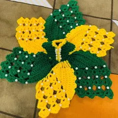 This sunflower-inspired dress is made with bright yellow and green yarn. The large, petal-like design is decorated with white pearls, giving it a fresh and cheerful look.