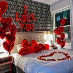 A classic and powerful statement for any romantic occasion. This hotel room setup features bold red "I Love You" foil balloons, heart-shaped balloon bouquets, and a heart on the bed made with LED candles for a safe and beautiful surprise.