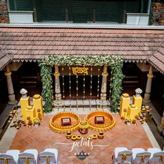 An overhead view of the Haldi setup in the courtyard, showcasing the symmetrical arrangement of the decor. The bright yellow elements stand out beautifully against the traditional terracotta tiles.