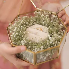 A close-up of a beautiful ring platter, with the rings nestled in a bed of baby's breath inside a geometric glass box. This is an example of how I elevate even the smallest details of a ceremony.