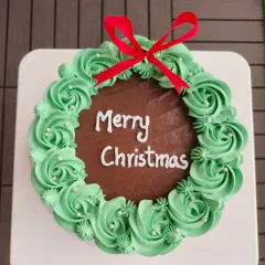 A top-down view of my Christmas wreath cake, showing the detailed buttercream piping and festive red ribbon. It's a chocolate cake that tastes as good as it looks.