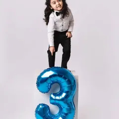 Standing tall on his third birthday! This portrait captures the proud and playful nature of a three-year-old, using a simple block and a number balloon.