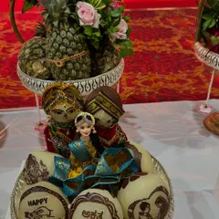 A special platter for an engagement ceremony, featuring personalized coconuts with "Happy Engagement" and the couple's initials. The arrangement is completed with traditionally dressed dolls.