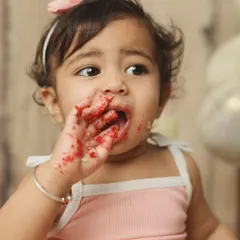It's all about the messy details. This close-up captures a baby girl enjoying every bit of her red velvet birthday cake.